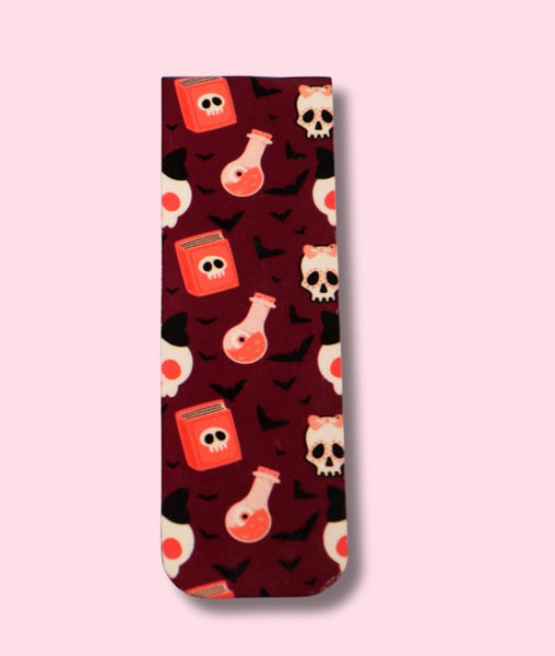 Magnetic Bookmark with a pattern of skulls and potion bottles on a pink background