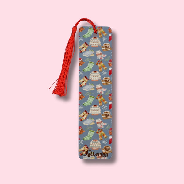 Decorative bookmark with sweaters, fuzzy socks, and hot chocolate on a pink background