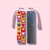 Colorful heart-shaped bookmark with tassel on a pink background