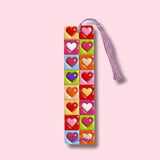 Colorful heart-shaped bookmark with tassel on a pink background