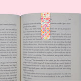 Open book with a colorful heart-patterned bookmark on a pink background