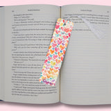 Colorful heart-patterned bookmark on an open book with a pink background